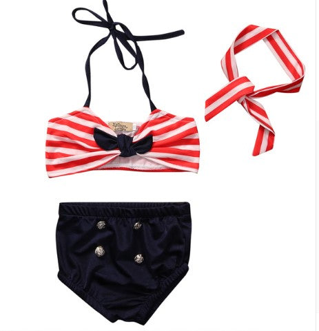 Blue bathing suit with 4 gold buttons, a red striped halter top and matching red stripe headband.