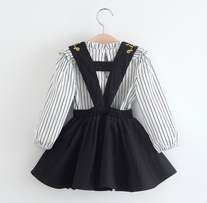 ruffled striped long sleeve shirt with black halter dress. Gold stitching lines the front and back of the straps. 