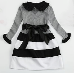 Black, grey and white long sleeved dress with ruffle sleeaves and collar. A thick ribbon slides around the waist and ties in a big bow. 