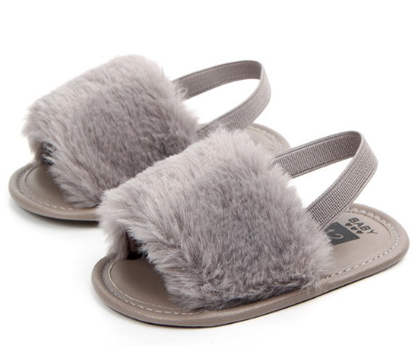 These adorable slippers come in 4 colors (beige, black, grey and pink) and have an elastic strap in the back to secure the slipper. The front of the slipper has a puff of faux fur to cover those little toes. We love this addition to our shoe collection!